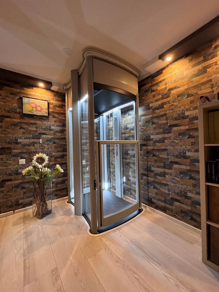 Senkrechtlift myHomelift in einer Ecke eines Wohnraumes mit geschlossener Tür