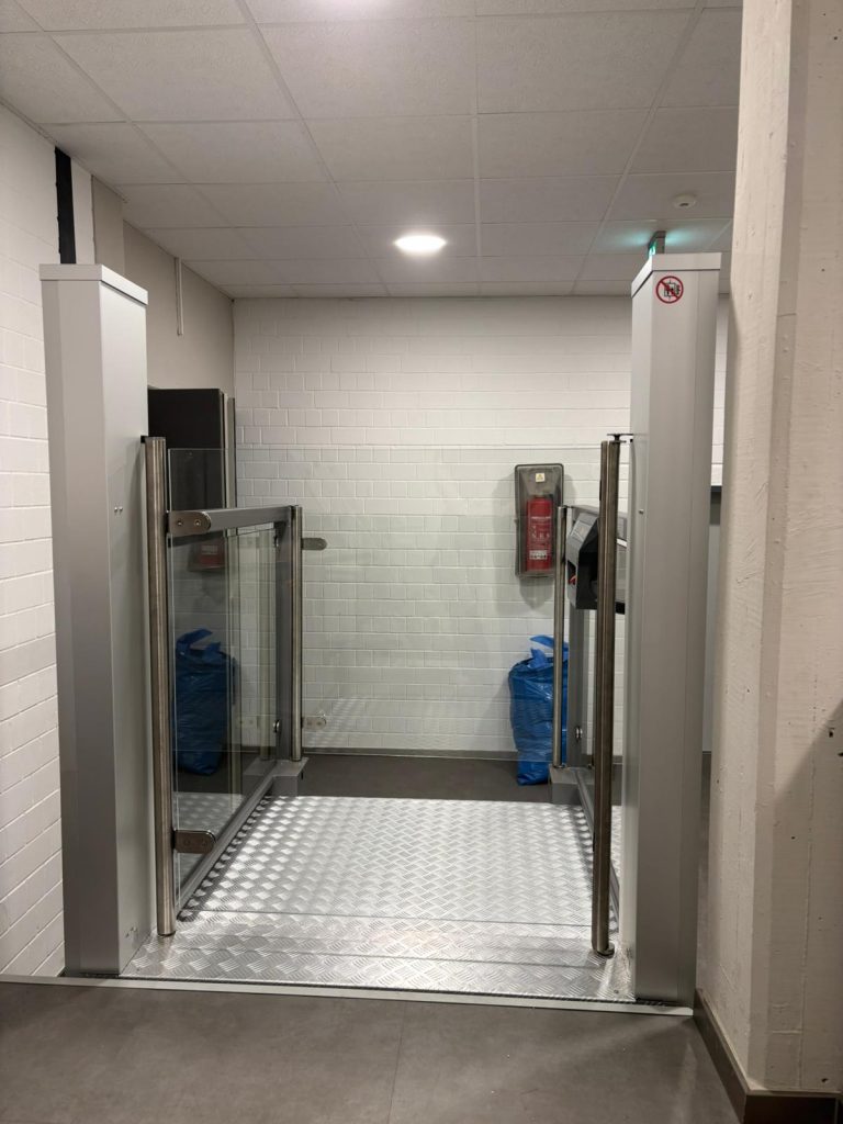 Plattformlift im abgesenkten Zustand, seitlich neben einer Treppe installiert.