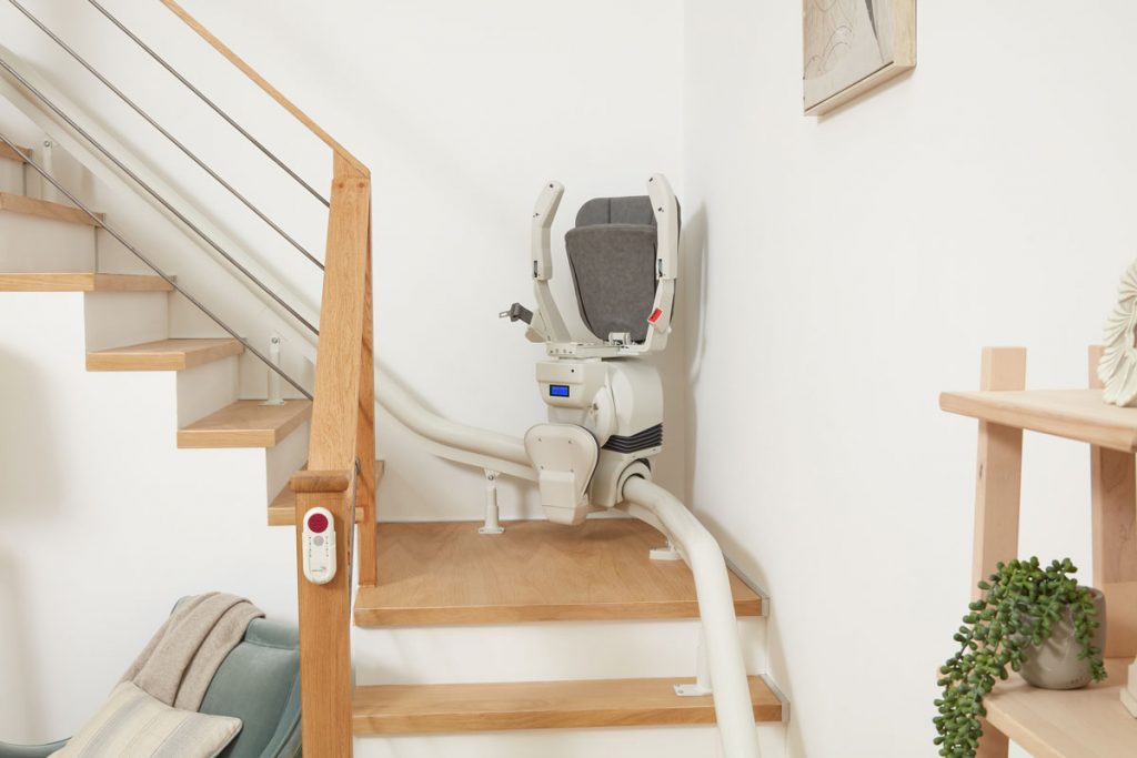 Ein eingeklappter Ultimate Treppenlift in der Ecke einer Treppe.