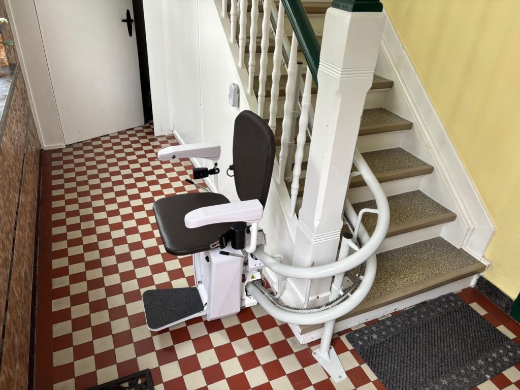 Trepenlift Alpha mit schwartem Sitz am uteren Ende einer Treppe